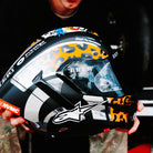 Person holding a colorful motorcycle helmet with visible branding