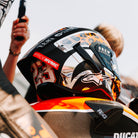 Person wearing a helmet with branding on a motorcycle, with a blurred background